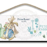 Beatrix Potter Peter Rabbit sitting next to watering can wooden sign