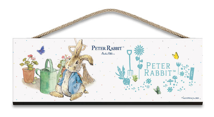 Beatrix Potter Peter Rabbit sitting next to watering can wooden sign